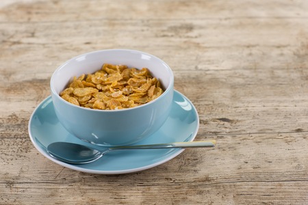 A big cup filled with cornflakes on a wooden table.の写真素材