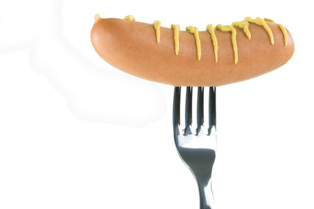 A raw sausage decorated with mustard pierced on a fork, isolated on white with copyspace.の写真素材