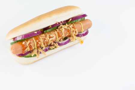 A fresh hotdog with sausage, onions, cocumbers, ketchup and mustard isolated on white.の写真素材