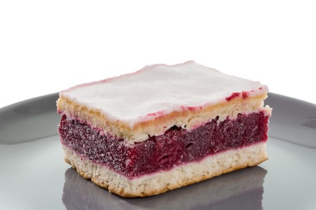 An icing cake with cherry gelantine, on a grey plate and a white background.の写真素材