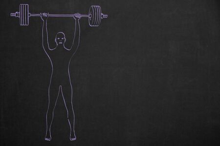 A bodybuilder with a dumbbell painted with chalk on a dark chalkboard.の写真素材