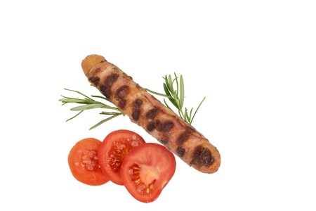 A grilled sausage decorated with tomato slices isolated on white.の写真素材
