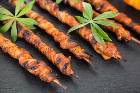 Some wrapped meat spits on a slate decorated with some woodruff.の写真素材