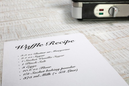 A perspective view from a waffle recipe with a waffle iron in the background.の写真素材