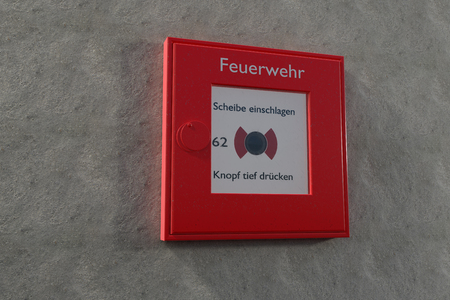 A german fire alarm box on a grey wall with copyspace.