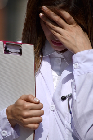 Cute Colombian Female Medical Professional And Sadness Wearing Lab Coat With Clipboardの写真素材