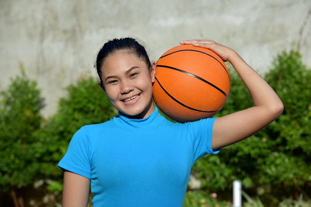 Smiling Sporty Asian Female Basketball Player With Basketballの写真素材