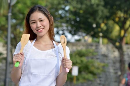 Happy Beautiful Asian Female Cook Chef Wearing Apron With Utensilsの写真素材