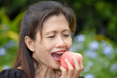 Female Senior And Happiness Eating An Appleの写真素材