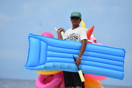 Filipino Man Walking On Beach With Floatation Raft