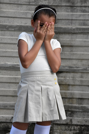 Crying Philippina Female Kid Wearing Skirt In Front Of Wallの写真素材