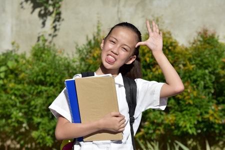 Filipina School Girl Making Funny Faces With School Booksの写真素材