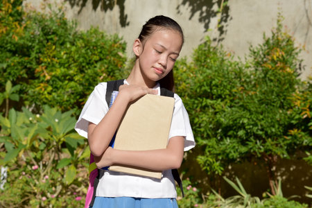 Sleepy Beautiful Filipina School Girl With Notebooksの写真素材