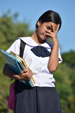 Beautiful Female Student Under Stress Wearing School Uniform With School Booksの写真素材