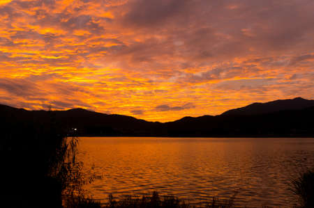 vivid red sunrise over pond in japanの写真素材