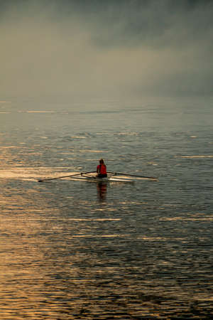 rower in the early morning rowing on the riverの写真素材