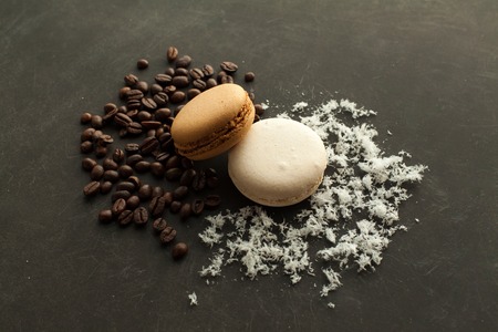 Coffee and coconut macaroons on the dark background with coffee beans and coconut chips.の写真素材