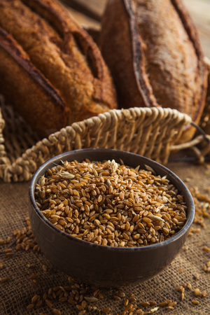Bowl full of rye on sackcloth with loaf of bread. Healthy organic ingridients for diet.の写真素材