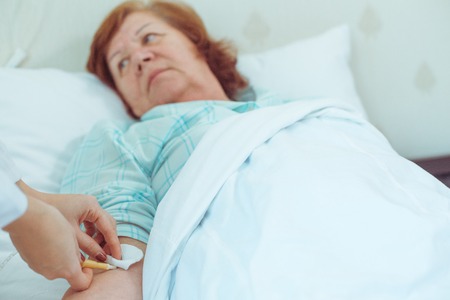 Injection to elderly woman in hospital, professional help to sick people. Preparation to surgery.の写真素材