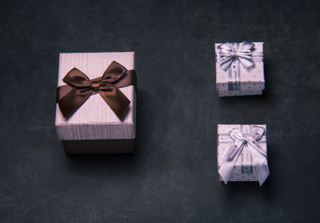 Big and small gift boxes on dark background. What is better, one big present, or two small. Presents...