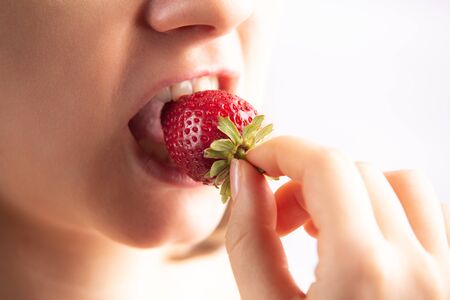 Closeup of a woman mouth eating strawberry.の写真素材