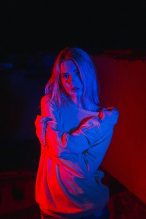 Blond woman into neon light. Nightclub life in the evening.