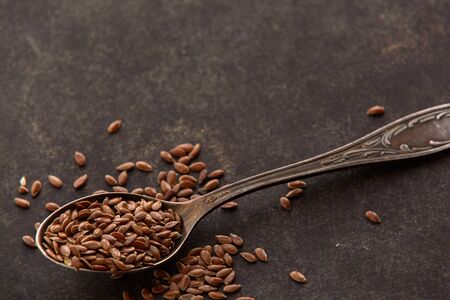 Flax seeds into spoons on dark background. Ingredients for healthy lifestyle meal. Full of vitamins and minerals food.の写真素材