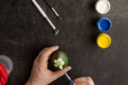 Woman painting with watercolors on egg to prepare Easter eggs.の写真素材