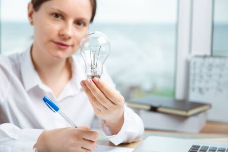 Woman holding lamp tube in hand as a symbol of inspiration and innovation. Fresh look at project at...