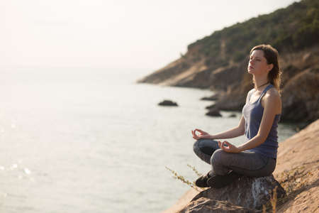 Young woman meditating on the rock near to seaside.の写真素材