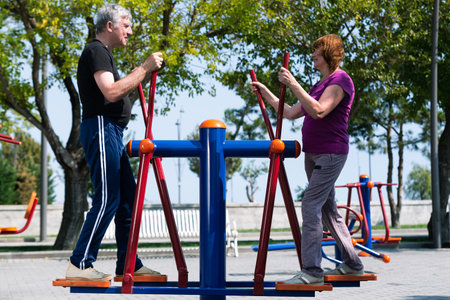 Senior couple doing sport exercises at sport ground. Retired man and woman making cardio trainings.