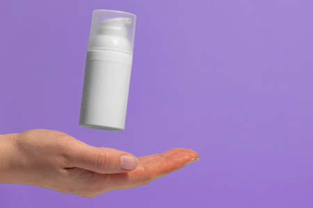 Woman's hand with floating cosmetic product without a brand, free space for text. Making an advertisement for sunblock moisturizer.の写真素材