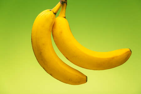 Ripe yellow bananas on green background, healthy nutrition full of vitamins for a healthy lifestyle.の写真素材