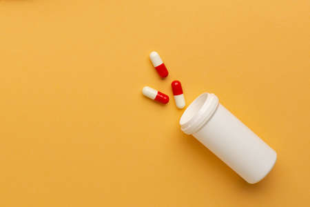 Close up of pills on orange background, concept of painkillers addiction. Lot of tablets, overdose. Antibiotics treatment.の写真素材