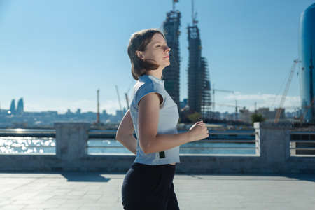 Running woman in town, morning activity for a healthy lifestyle. Athletic shape young girl in...
