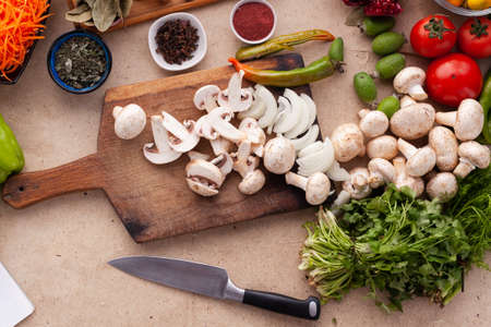 Sliced mushrooms and onion on a wooden table with vegetables for cooking a vegetarian meal. Healthy...