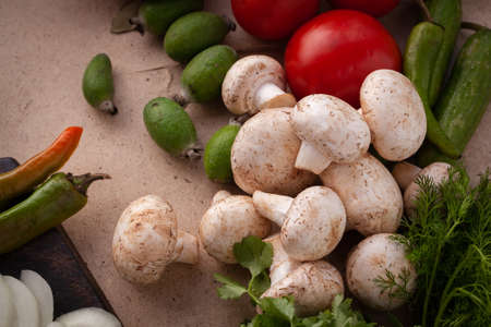 Ingredients for cooking a vegetarian meal without meat, raw mushrooms, and cucumber on cutting board.の写真素材