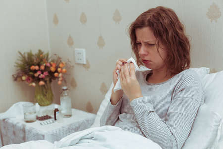 Woman in bed coughing and feel sick, symptoms of , high temperature, and cough.
