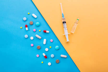 A lot of pills and syringe with injection as a symbol of choice antibiotics against vaccine. Insulin and pills for people to control sugar in the blood.の写真素材