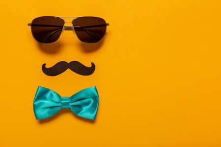 Glasses, mustache, and blue bow as a symbol of father's day with free space for text, greeting card for holiday. Celebration of a family holiday.の写真素材