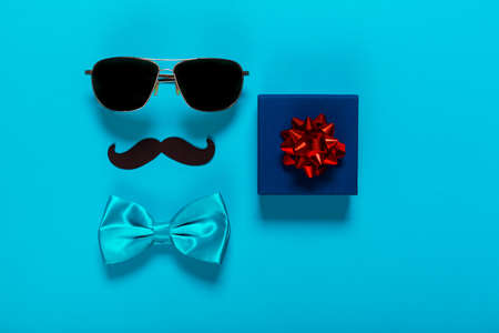 Glasses, mustache, and blue bow with present box as a symbol of fathers day, greeting card for holiday.の写真素材