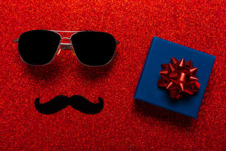 Glasses and mustache as a symbol of fathers day with the present, greeting card for holiday.