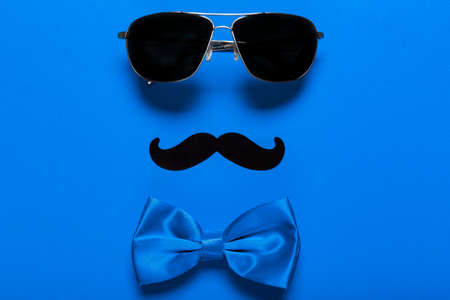 Glasses, mustache, and blue bow as a symbol of father's day, greeting card for holiday. Celebration of a family holiday.の写真素材