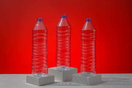 Plastic bottles on a red background as a symbol of ecological catastrophes. Empty bottles from water as an advertisement for recycling.の写真素材