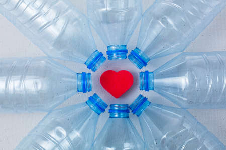 Plastic bottles on a white background with a heart shape figure as a symbol of ecological...