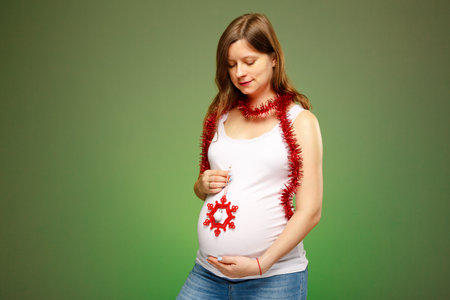 Pregnant woman with Christmas decorations, expecting baby birth on Christmas eve.の写真素材