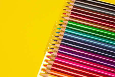 Different colors pencils on yellow background, set for school to draw on the lesson. New sharp...