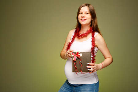 Pregnant woman with a gift, happy face expression, getting present on Christmas eve. What to give a pregnant woman in the new year.の写真素材