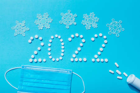 2022 new year written with white pills and protective face mask, the concept of medical treatment. Free space for text with prescription. How to celebrate when you are sick.の写真素材
