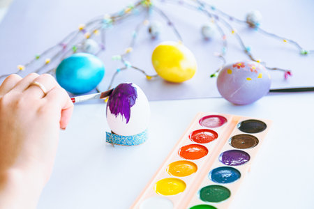Woman hand painting easter egg with watercolors, preparation for egg hunt game. Happy easter congratulation symbol.の写真素材